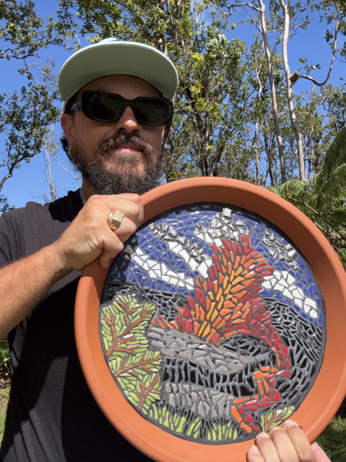 Rafael Poscai holding one of his volcanic mosaics outdoors