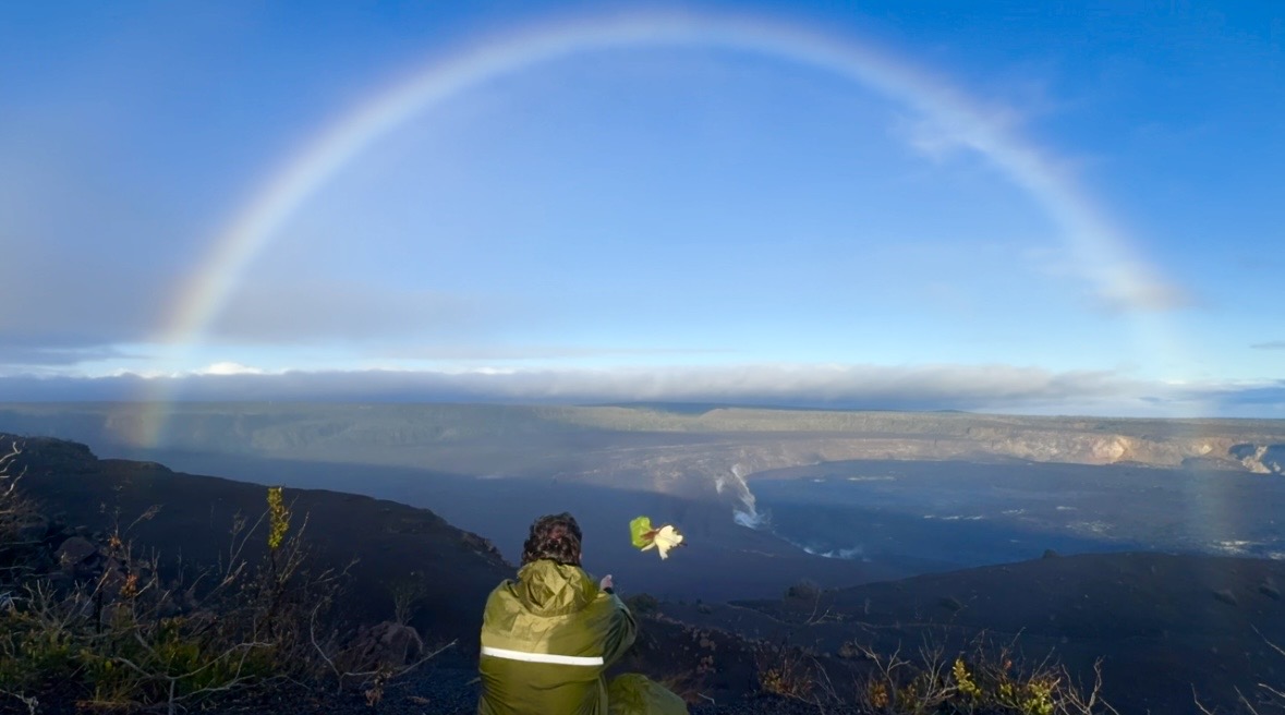 Rafael looking over Kīlauea’s caldera beneath a rainbow