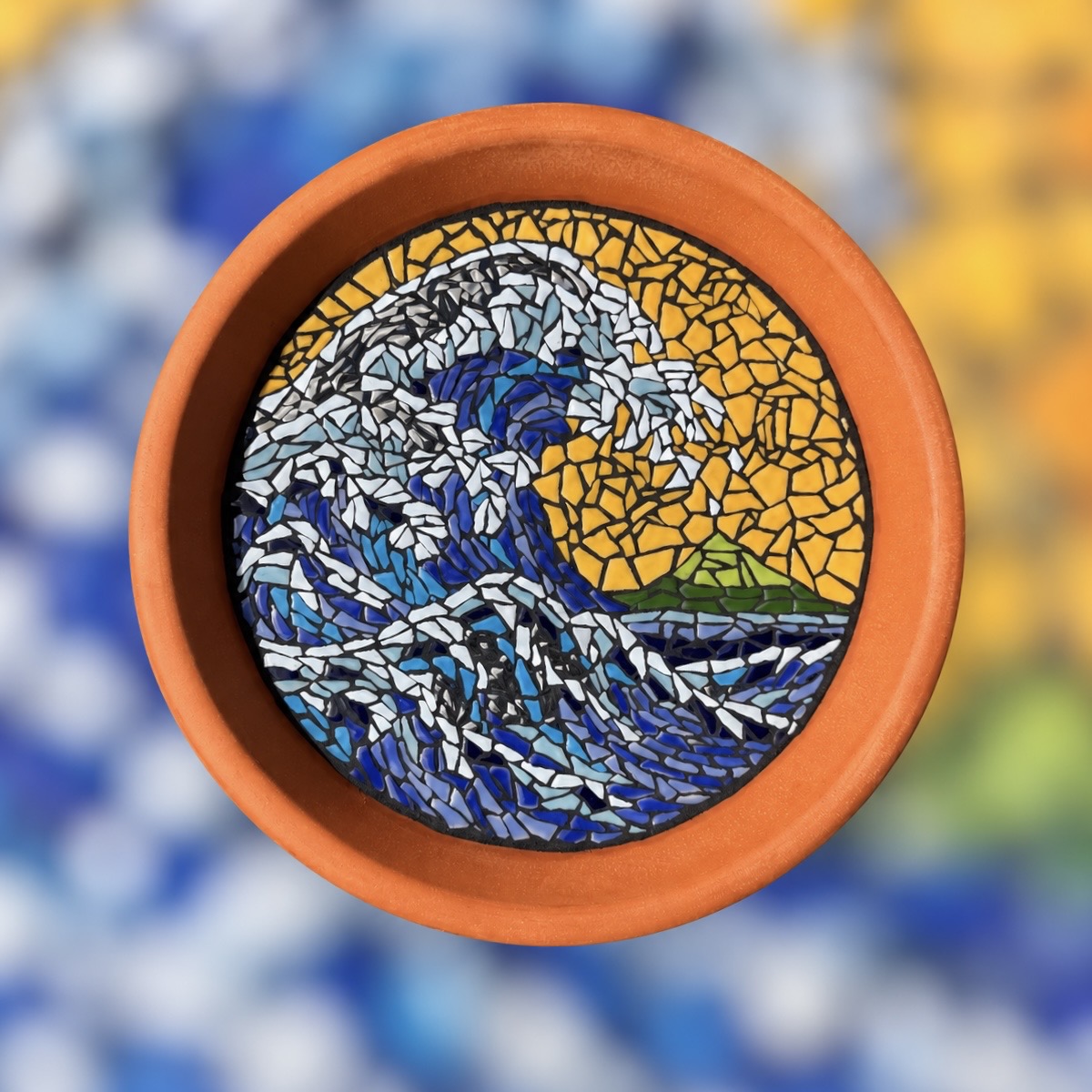 Unfinished blue and white wave mosaic with pencil outlines in a terracotta dish